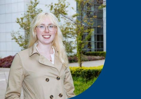 Smiling SEAM+ student with blonde hair and beige coat