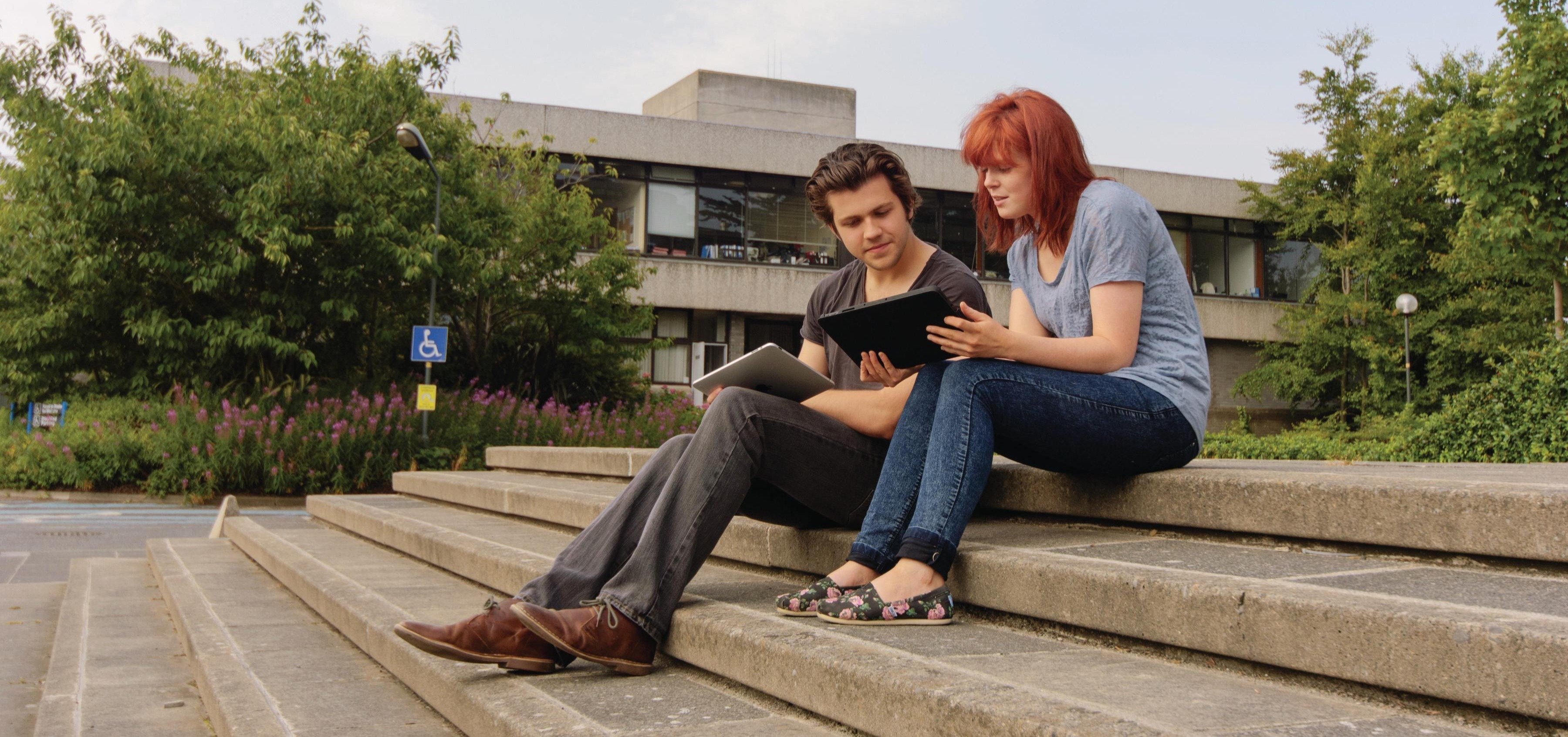Students sitting outdoors on UCD Belfield campus.