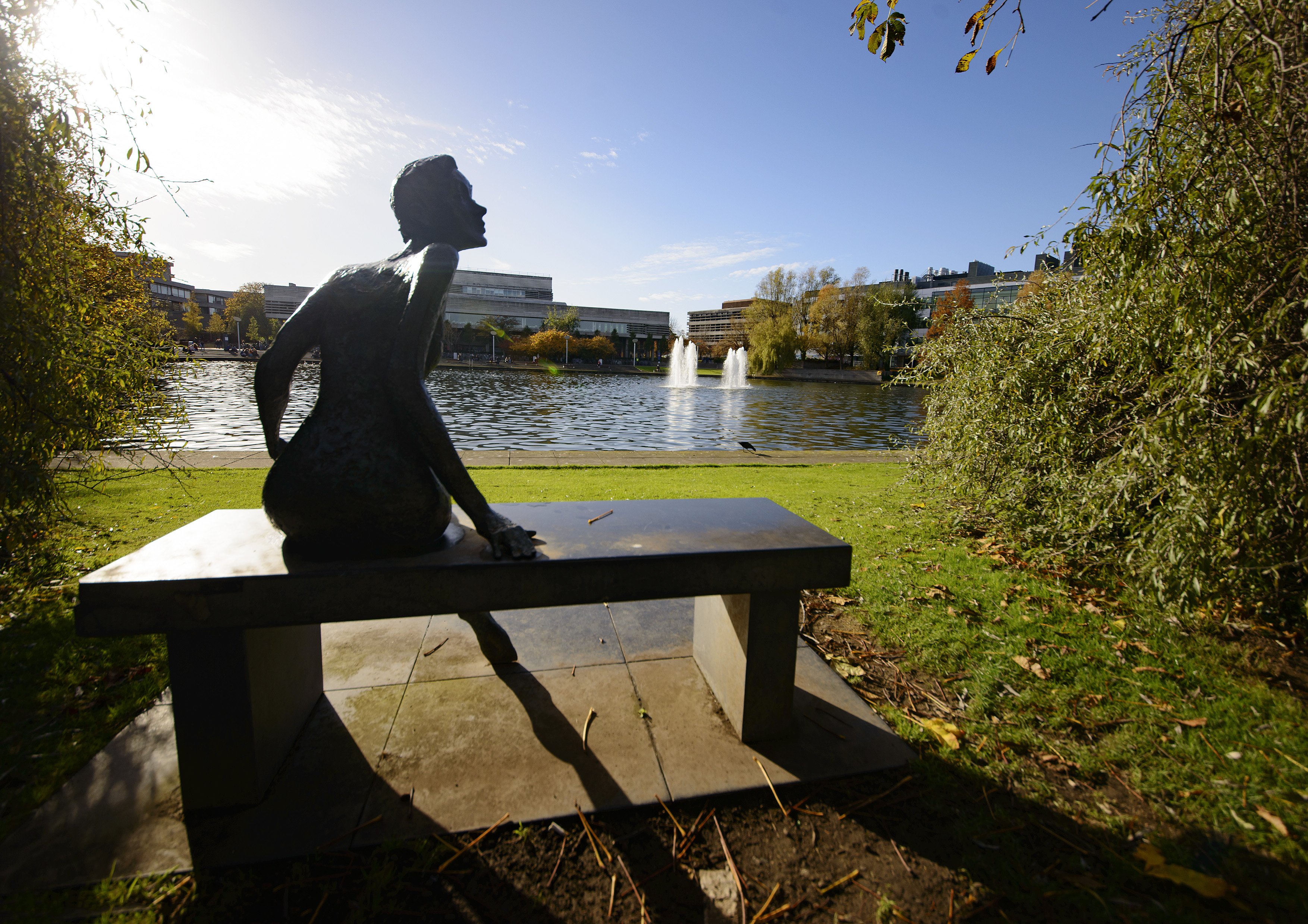Statue of a woman on a bench with a lake in the background