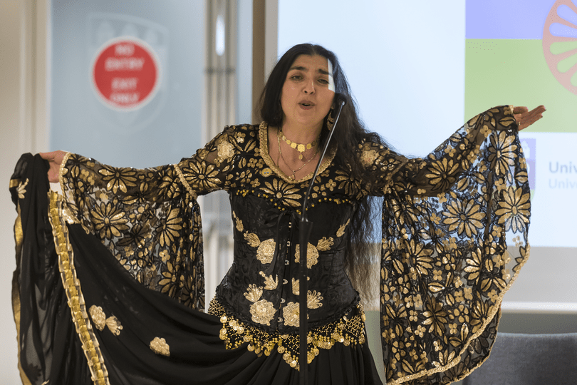 A UCD student wearing traditional clothing singing for the celebration of international roma day.