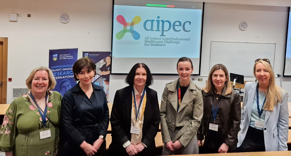 A group of people standing together smiling in front of a projector screen