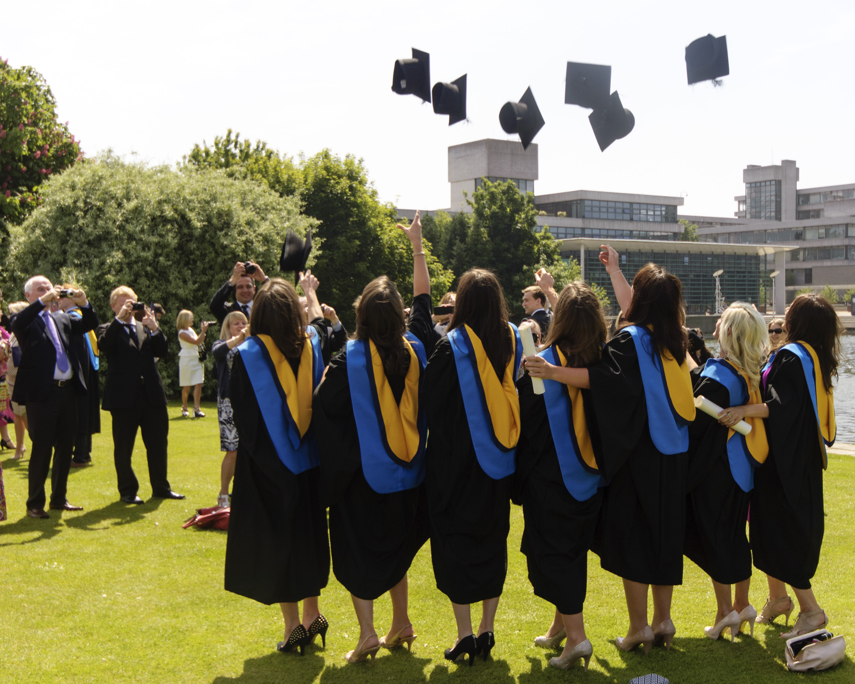 Graduates throwing caps in the air in front of lake