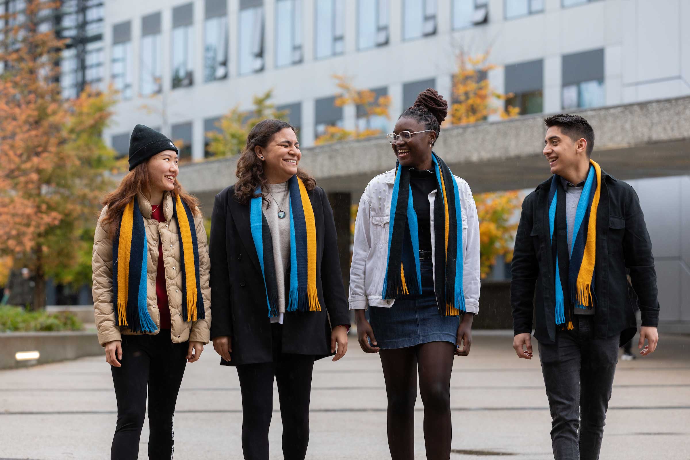 A group of four students who are chatting and laughing with one another on a campus tour.