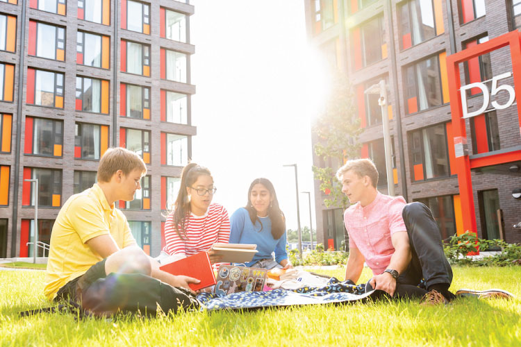 International students on the grass on a sunny day outside new UCD student accommodation