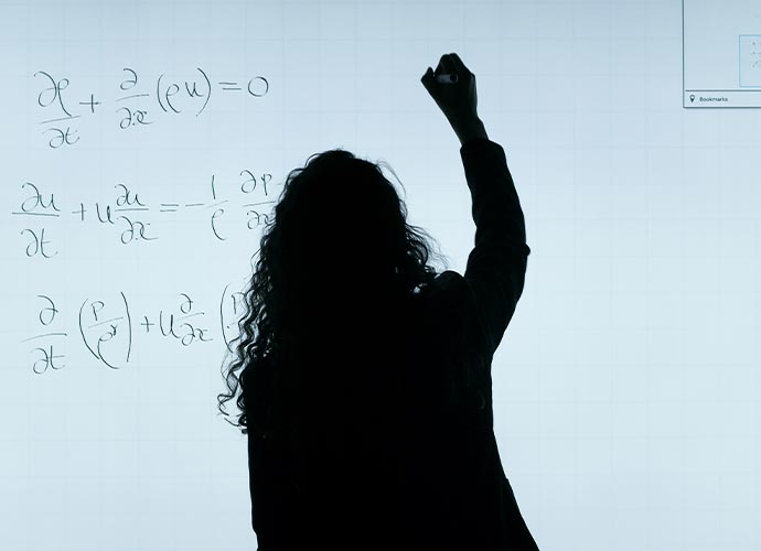 Silhouette of a person with curly hair writing mathematical equations on a large whiteboard or digital screen. The board displays differential equations with partial derivatives.
