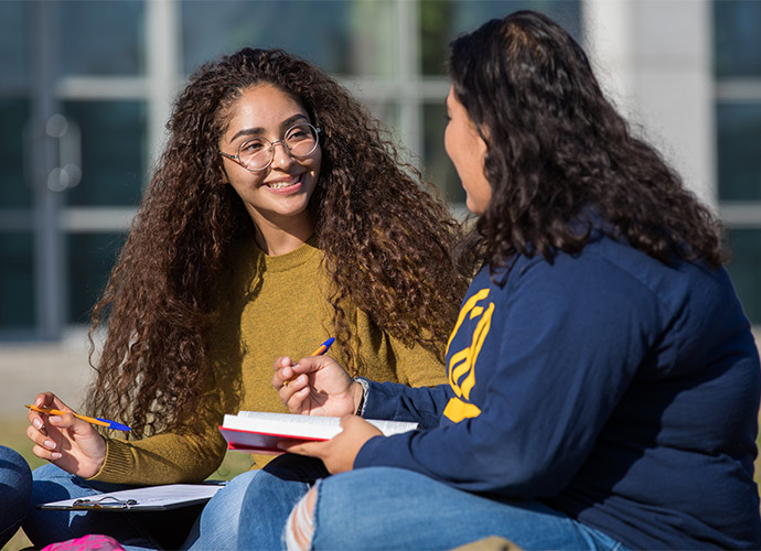 Two young women smiling and chatting.