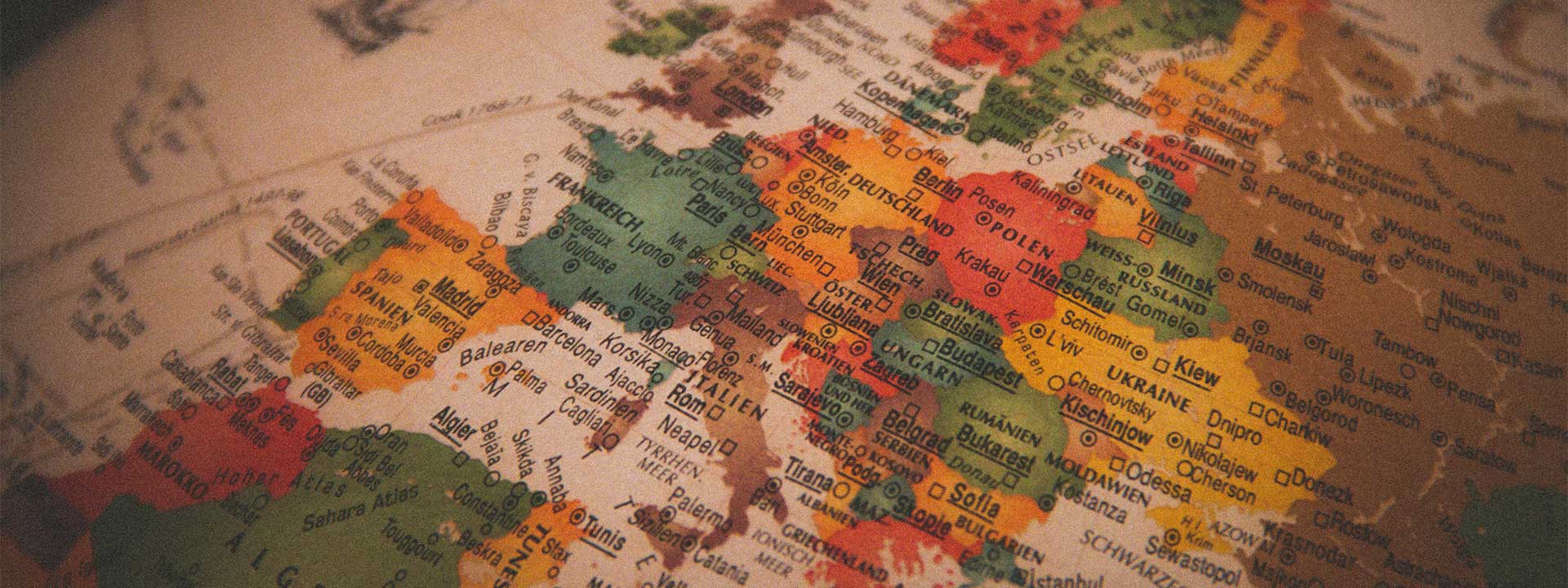 Close-up of a vintage-style map of Europe showing countries including Spain, France, Germany, Italy, Poland, and Ukraine, with major cities like Madrid, Paris, Berlin, Rome, and Warsaw labelled.