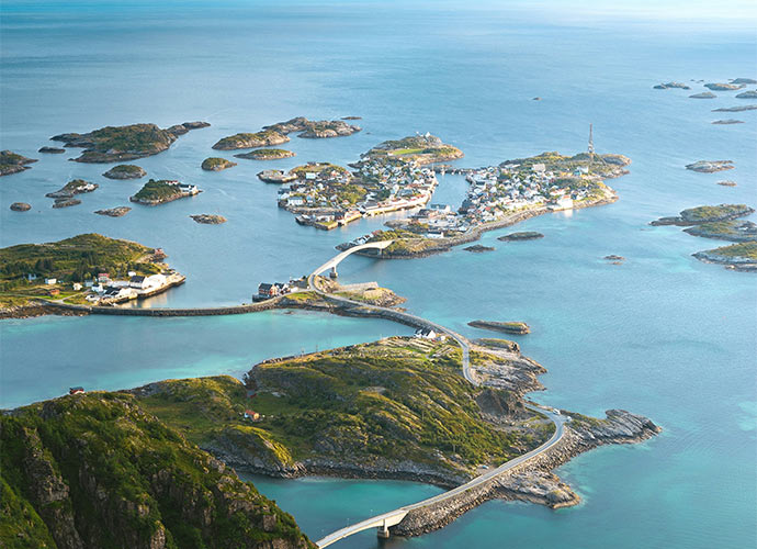 An aerial view of a small coastal village connected by winding bridges across several rocky islands.