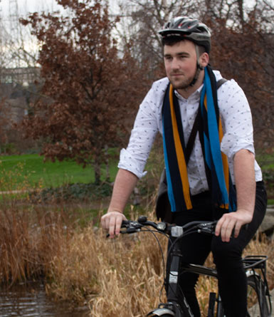 UCD Student wearing a UCD scarf cycles past a pound on UCD campus.