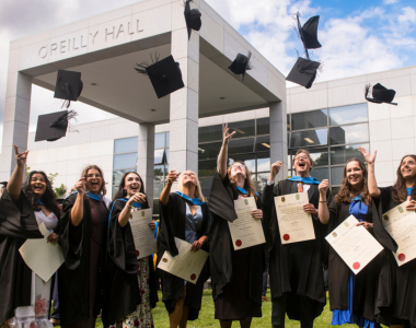 Group of students in black graduation gowns throwing hats in the air