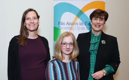 Three women standing in front of a Growing up in Ireland stand