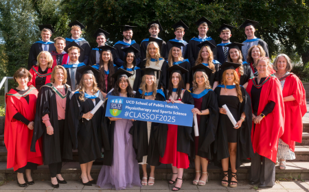 Group of smiling graduates and academics holding a blue Class of 2025 sign