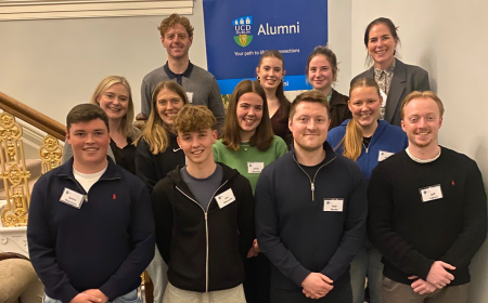 A group of people standing on a stairs smiling to camera