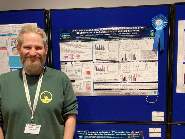 male research scientist standing in front of scientific poster