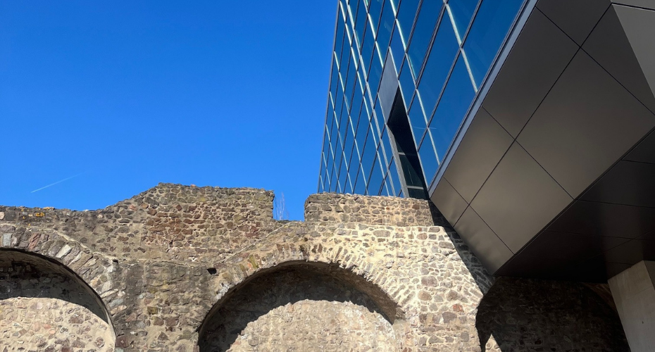 New modern building built around historical stone wall, blue skies