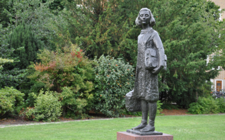 Statue of Anne Frank in front of trees