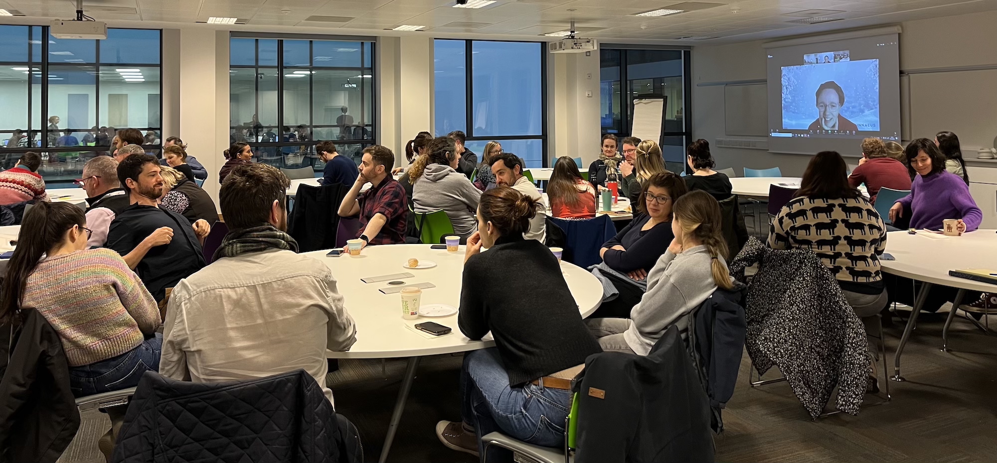 Group sitting in a large room with projector screen