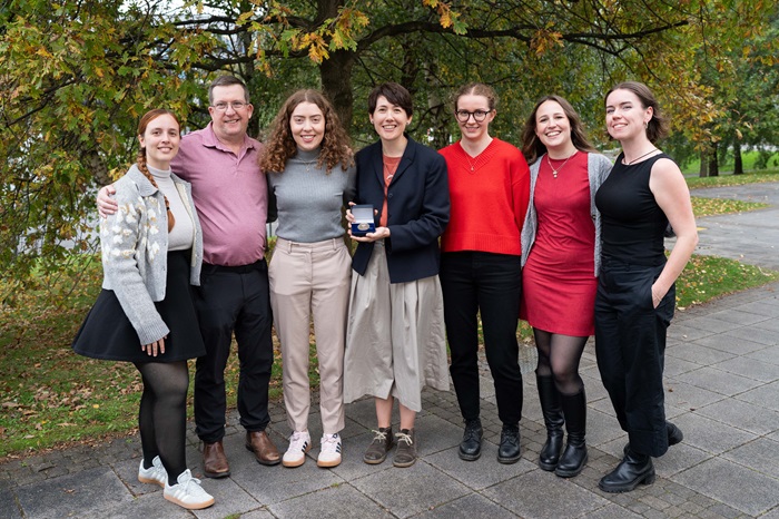 People smiling and woman holding a box with medal inside